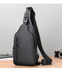 Detail of grey crossbody sling bag with USB charging port on a wooden table setup