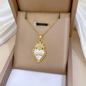 Close-up of golden heart crown pendant with white enamel and sparkling rhinestones