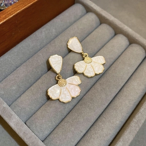 Elegant white floral earrings with gold edges presented in a gray velvet jewelry box