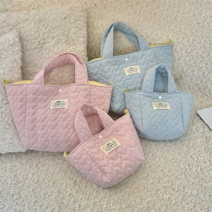 Detailed view of pink and blue heart quilted handbags in small and large sizes