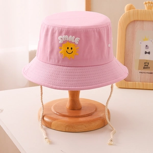 Détail d'un chapeau de soleil rose en coton avec broderie smile et une mentonnière