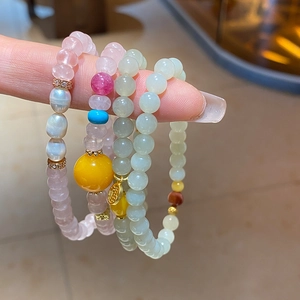 Gros plan de bracelets en perles de jade, ambre, perles et breloques dorées