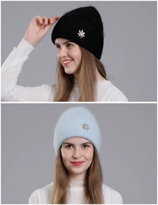 Detailed view of plush knit beanies in black and light blue with leaf pearl brooch