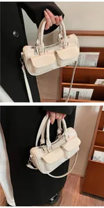 Detail of cream barrel bag with dual front flap pockets and versatile shoulder strap