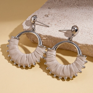 Macro detail of beige leather wrapped round earrings with silver studs on stone
