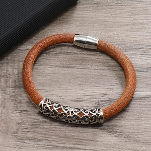 Close-up of brown braided leather bracelet with engraved silver metal tube and magnetic clasp