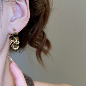 Close-up of beaded hoop earring on model featuring acrylic and wood textures