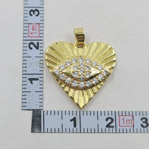 Detail shot of a gold heart evil eye pendant with measurements on a white background