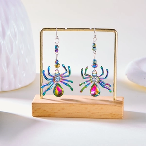 Colorful spider earrings with white rhinestones and large gemstones on a wooden display stand