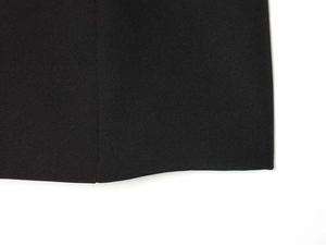 Gros plan sur le tissu noir texturé et les coutures de qualité de l'ourlet de la robe