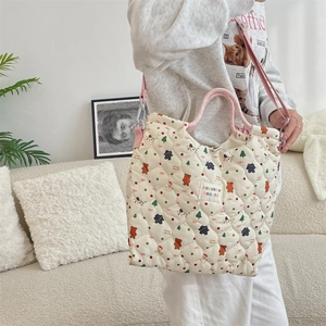 Sac fourre-tout matelassé avec motifs festifs et anses roses porté par un mannequin