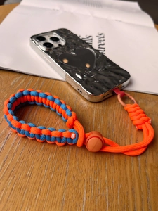 Close-up of woven orange and blue paracord phone wrist strap with adjustable buckle