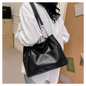 Dettaglio della grande borsa tote in pelle PU nera con catena e tasca frontale