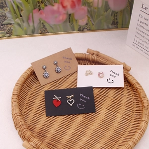 Assorted pearl and heart earrings presented on thank you cards in a woven tray