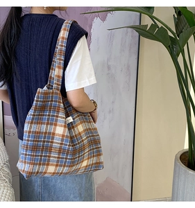 Détail d'un grand sac cabas en laine à carreaux vintage avec étiquette tissée élégante