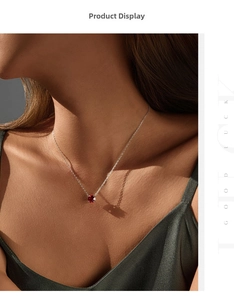 Close-up of S925 silver necklace with ruby red round pendant on elegant silk dress