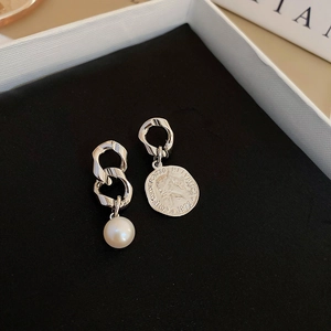 Detail of asymmetric earrings with silver coin relief and elegant white pearl pendant