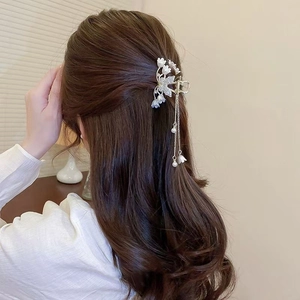 Détail de la pince à cheveux muguet avec perles et longs pompons sur la coiffure