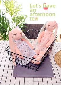 Detailed view of two pink plush rabbits in floral dresses inside a black metal basket