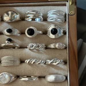 Silver rings set with black onyx and pearls in a wooden jewelry display case