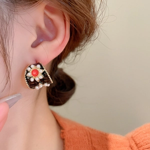 Gros plan d'une boucle d'oreille vintage avec pierre rouge et perles sur le mannequin