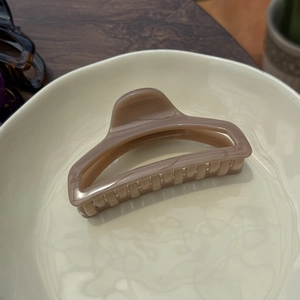 Detail of a large 10cm minimalist cream hair claw clip on a ceramic plate with wood backdrop