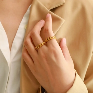 Close-up of golden hollow cuban chain rings worn by a model in professional office attire