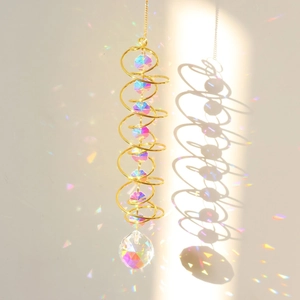 Detail of golden spiral wind spinner with faceted crystal ball creating rainbow reflections