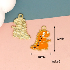 Detail view of 22mm orange enamel dinosaur pendants showing front and back textures