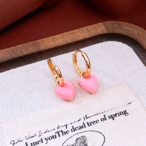 Close-up of French vintage gold hoops with pink enamel heart charms on a wooden tray