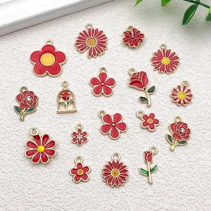 Detailed flat lay of red floral alloy enamel pendants with gold-plated daisy and rose designs