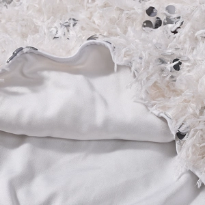 Macro view of white sequin fabric with faux feather trim and smooth inner lining