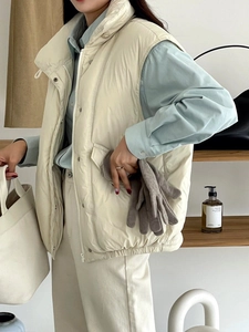 Primer plano de un chaleco acolchado beige con guantes de lana grises en un entorno cotidiano