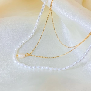 Detailed macro view of double-layered pearl necklace on elegant white silk fabric