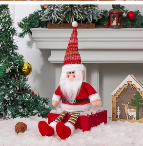 Détail du Père Noël en peluche avec longues jambes rayées sur boîte-cadeau rouge