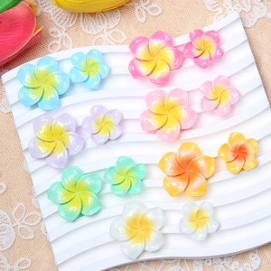 Colorful resin plumeria flower charms in two sizes and various gradient colors on display