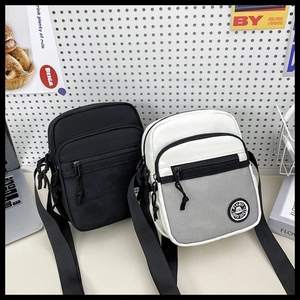 Detail of minimalist nylon messenger bags with front mesh pocket and logo patch
