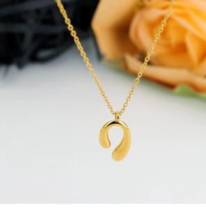 Macro shot of polished gold-plated horseshoe U-pendant with glossy mirror finish