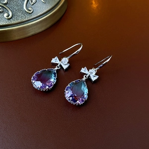 Détail de boucles d'oreilles argentées avec nœud violet et cristal sur cuir