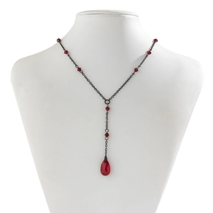 Close-up of Gothic Y-necklace with black chain and red teardrop crystal on a white bust