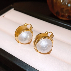 Boucles d'oreilles créoles dorées avec perles baroques sur fond de cuir beige élégant