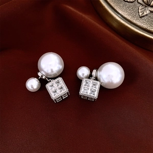 Detailed macro of a pearl drop earring with square zircon pendant on red velvet