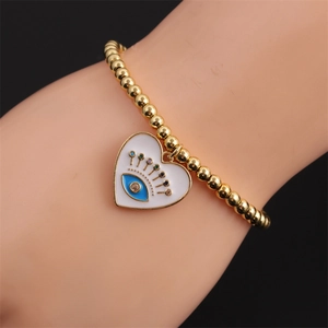 Macro shot of 18K gold plated beaded bracelet featuring a colorful evil eye heart charm