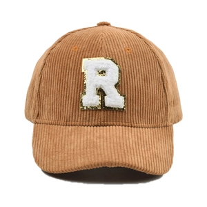 Detailansicht einer camelbraunen Cord-Baseballkappe mit glitzerndem Buchstaben-R-Aufnäher