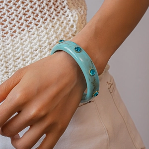Detail of light blue marble acrylic bangle with inlaid teal crystals on model