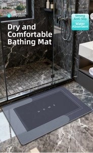 Detail of dark grey anti-slip diatomite bath mat with HOME text on marble floor