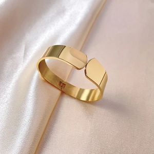 Minimalist gold titanium steel wide hinged bangle displayed on elegant beige satin fabric