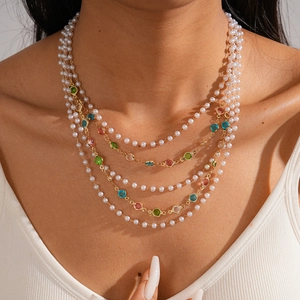 Detail of layered baroque pearl necklace with colorful gemstones and golden chains