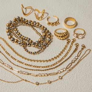 Flat lay of multiple 18K gold and silver plated stainless steel necklaces and rings