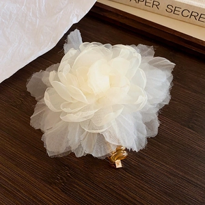 Elegant white organza flower hair claw clip with amber resin base on wood background